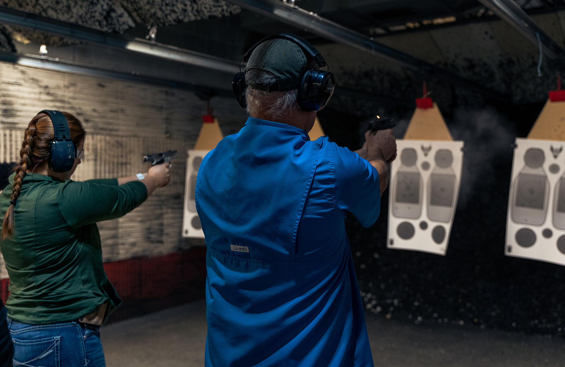 Man and women aim gun at indoor target