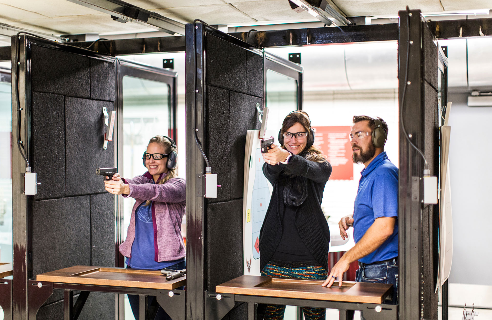Two women are shown how to point a gun at a shooting range